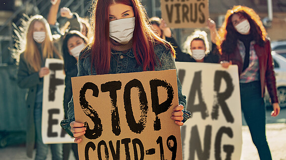 Frauen in Zeiten von Covid 19 Auf einer Demonstration halten Frauen mit Minde-Nasen-Schutz Plakate mit der Aufschrift "Stop Covid-19"