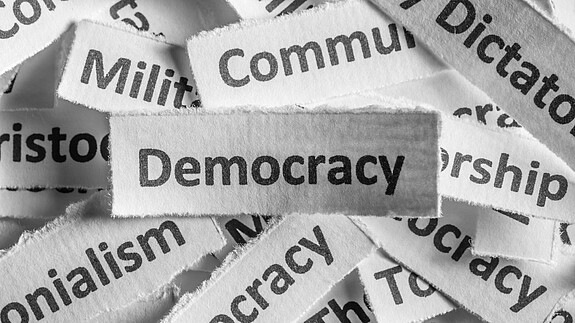 EWSA fordert Rücknahme der Richtlinie im Demokratiepaket Verschiedene Staatsformen sind auf Zettel geschrieben, die Demokratie liegt über allen
