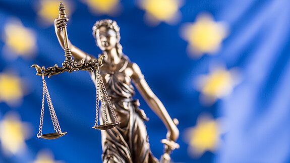 Justizia-Statue vor Europaflagge
