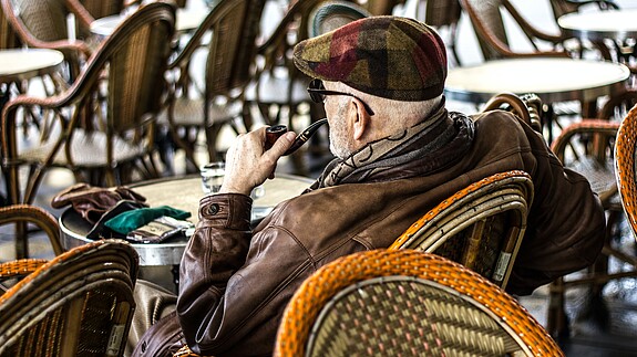 Tag der älteren Menschen Ein älterer Herr sitzt in einem Café und raucht Pfeife.