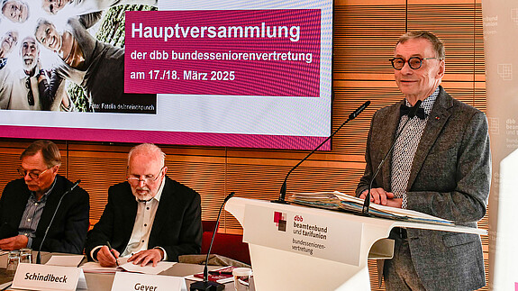 Ein Mann in Anzug steht an einem Rednerpult.