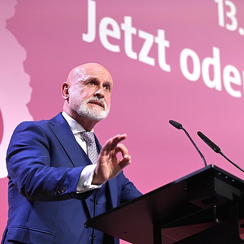 Ein Mann steht hinter einem Rednerpult und spricht in das Mikrofon