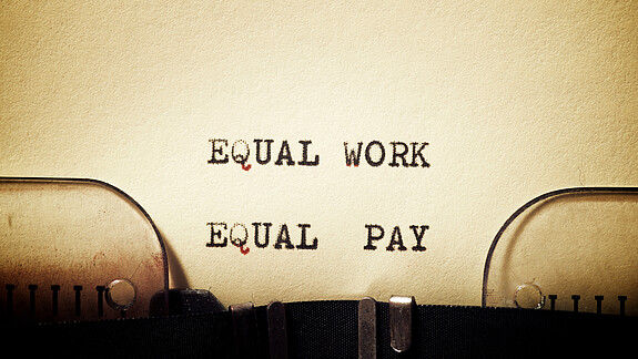 Equal Pay Day Auf einem in eine Schreibmaschine eingespannten Blatt stehen die getippten Worte "Equal Work - Equal Pay"