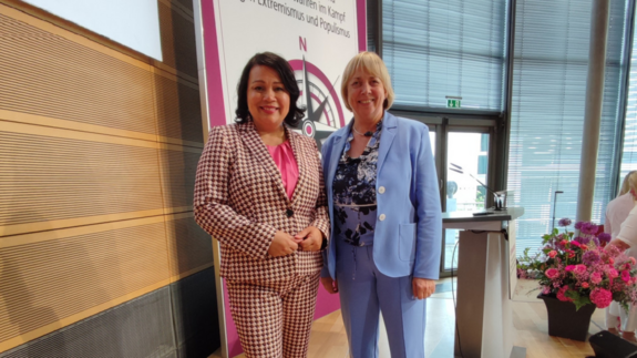 dbb Bundesfrauenvorsitzende Milanie Kreutz (links) und stellvertretende tbb Frauenvorsitzende Kerstin Knauer (rechts) auf der 19. Frauenpolitischen Fachtagung in Berlin. Zwei Frauen stehen auf einer Bühne und schauen in die Kamera