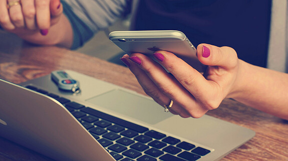 dbb fordert EU-Richtlinie zum Recht auf Nichterreichbarkeit Eine Person sitzt vor einem Laptop und hat ein Handy in der Hand