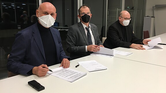dataport Tarifeinigung Drei Männer mit Mund-Nasenschutz sitzen an einem Tisch und unterzeichnen die Verhandlungsergebnisse.