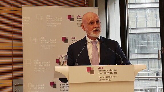 Zu sehen ist Volker Geyer, dbb Bundesvorsitzender der am Podium steht und zur dbb bundesseniorenvertretung spricht. 