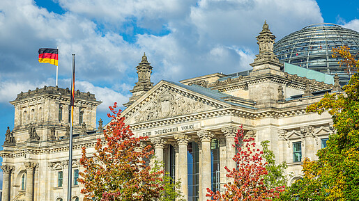 Reichstag building, seat of the German Parliament with national flag at sunset, Berlin